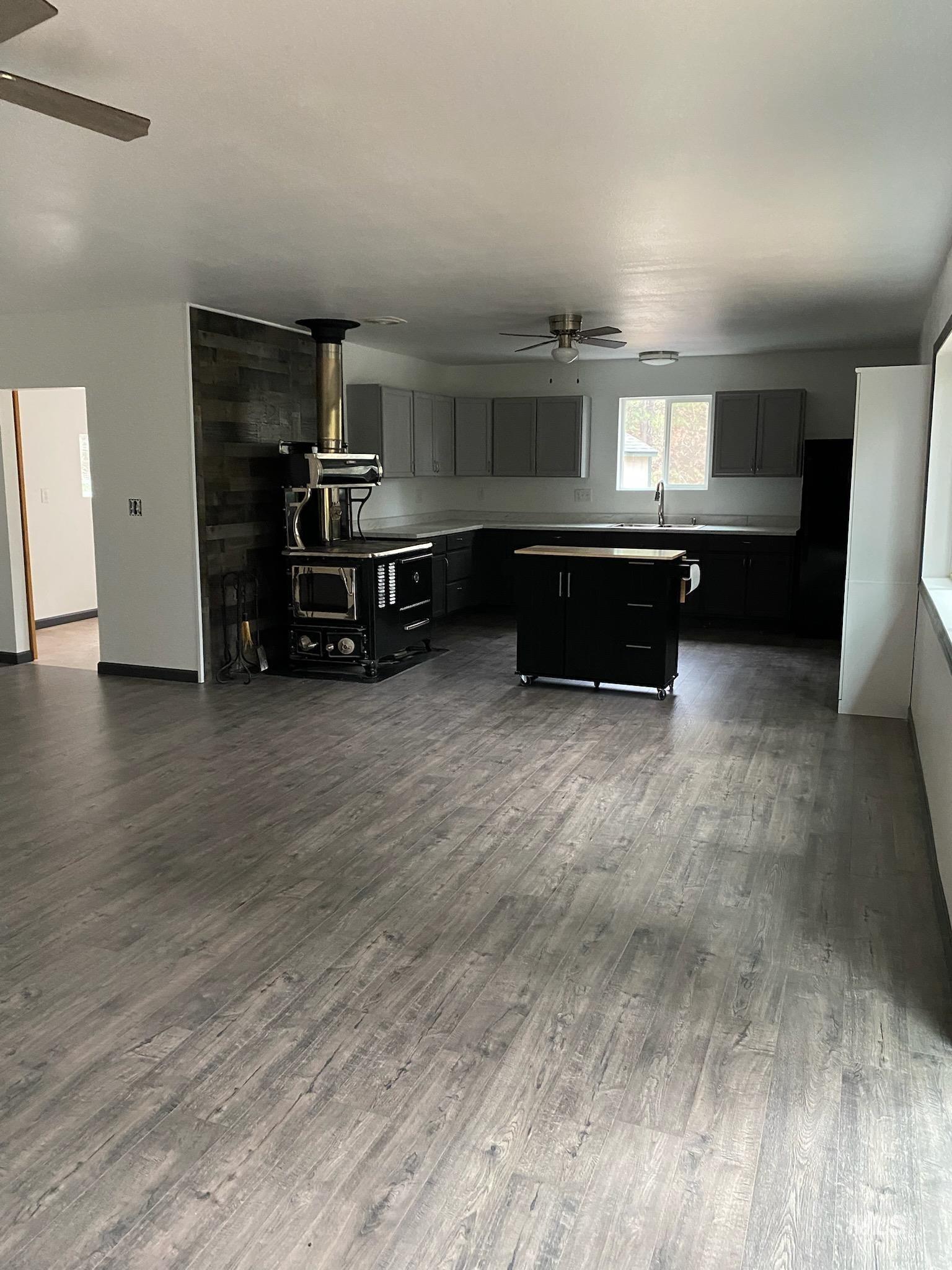 123 Conifer Lane Stites, ID 83552 - Photo 48 of 48 Kitchen with ceiling fan, a wood stove, a kitchen island, light countertops, and dark wood-style floors