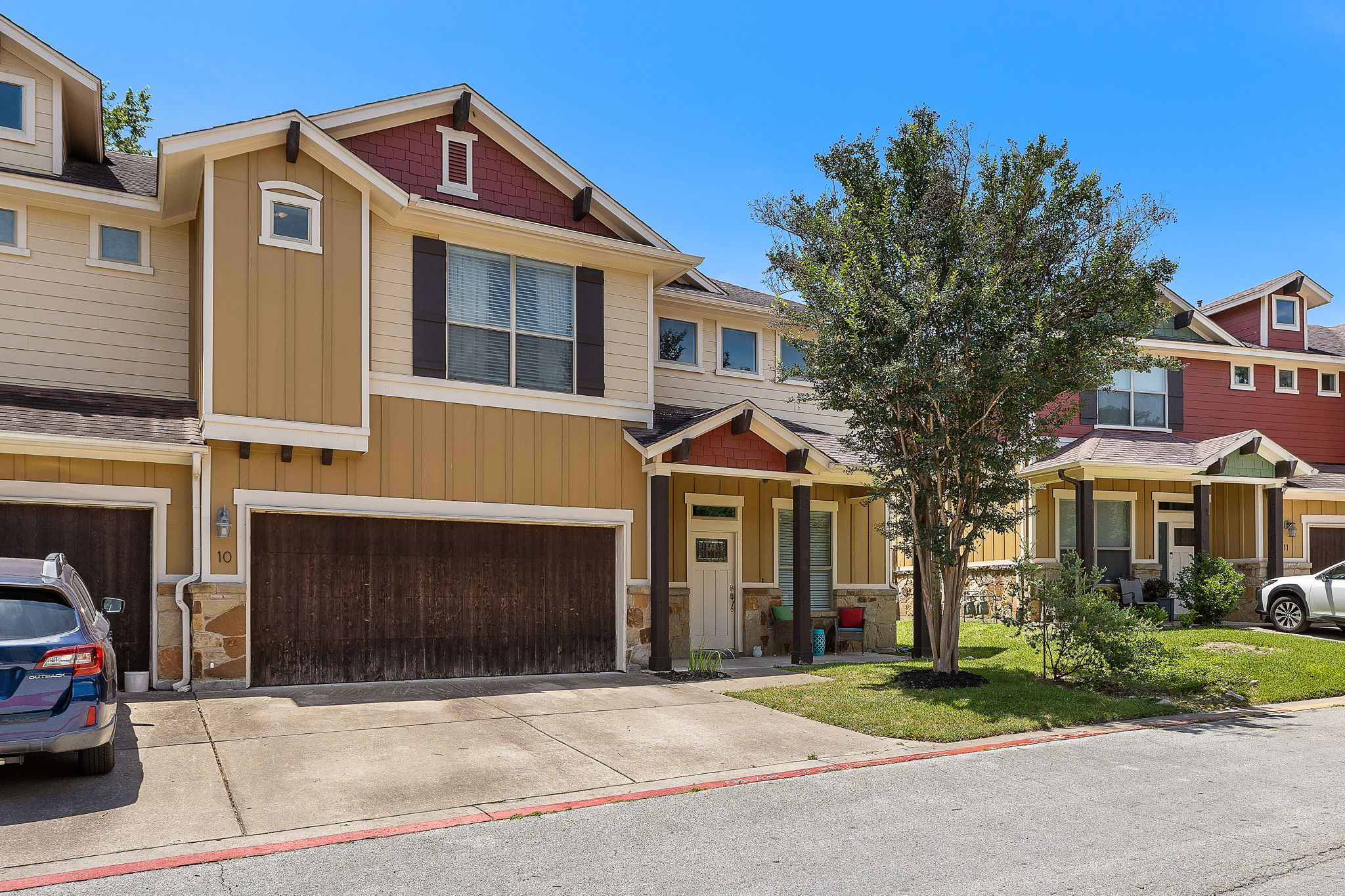 6708 Menchaca Road, Unit 10 Austin, TX 78745 - Photo 2 of 28 Craftsman-style facade featuring earth-toned siding, stone accents, a prominent two-car garage, and a covered entry porch