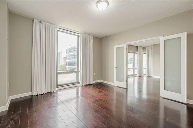 a view of an empty room with wooden floor and a window