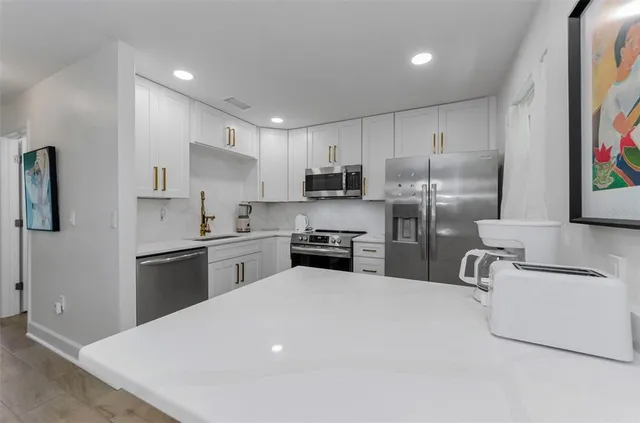 a kitchen with stainless steel appliances a refrigerator sink and white cabinets