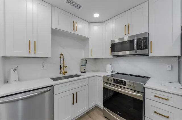 a kitchen with cabinets stainless steel appliances and a sink
