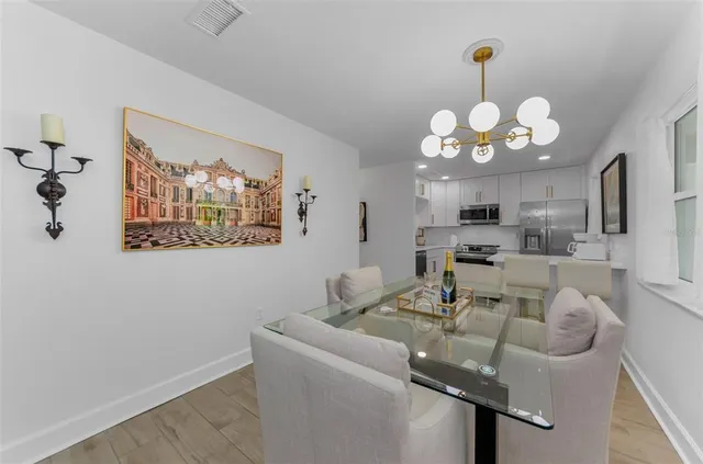 a dining room with wooden floor furniture and kitchen view