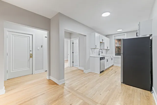 a view of a kitchen with refrigerator and white cabinets
