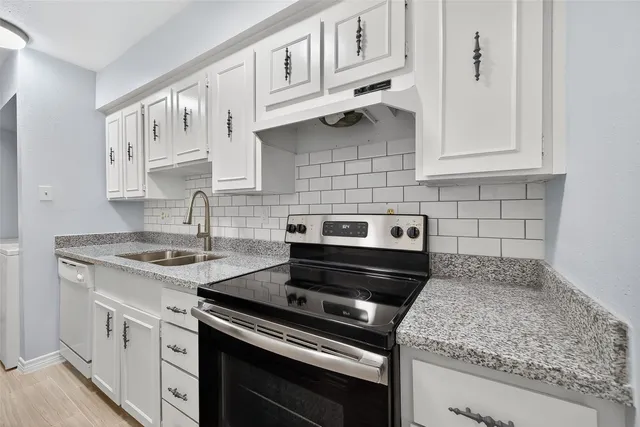 a kitchen with white cabinets and appliances