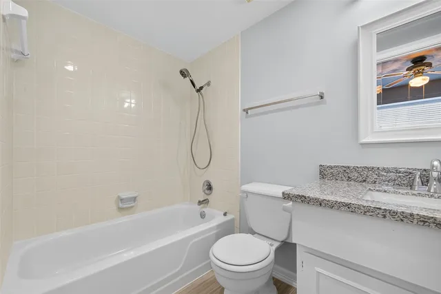 a bathroom with a granite countertop sink a toilet and a bathtub