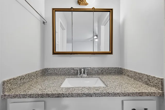a bathroom with a granite countertop sink and a mirror