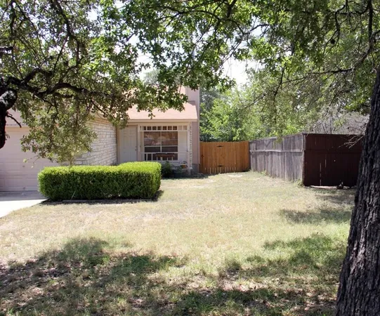 a view of backyard with large trees and wooden fence