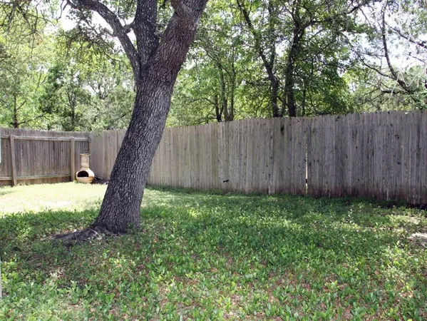 a view of a backyard with large trees and wooden fence