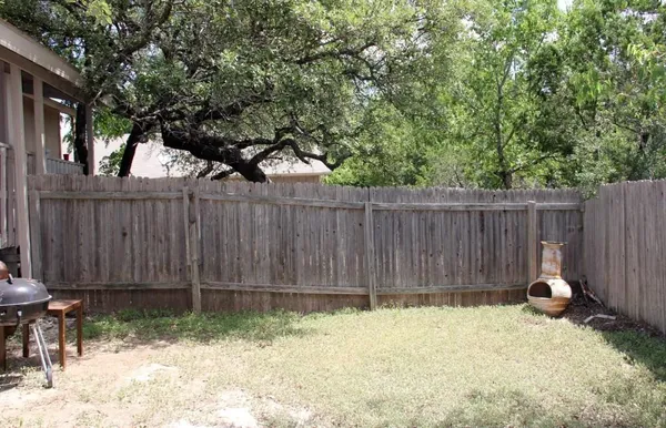 a backyard of a house with lawn chairs and wooden fence