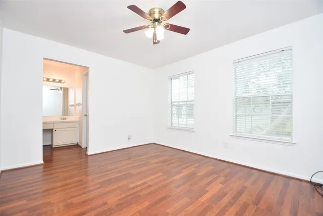 an empty room with wooden floor and a ceiling fan
