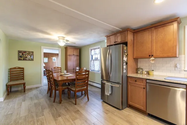 a kitchen with stainless steel appliances granite countertop a dining table chairs and a refrigerator