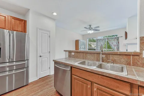 a kitchen with stainless steel appliances granite countertop a sink a refrigerator and a granite counter tops with white cabinets