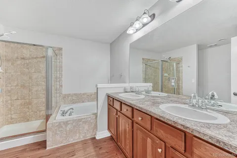 a bathroom with a granite countertop double vanity sink a mirror and a bathtub