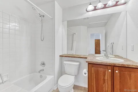 a bathroom with a granite countertop sink toilet and shower
