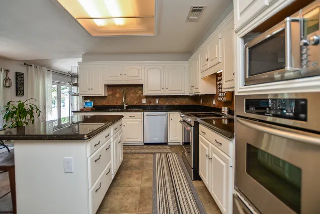 a kitchen with granite countertop a sink a stove top oven and cabinetry