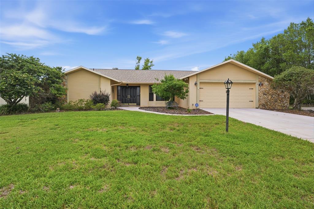 5227 Suwannee Road Weeki Wachee, FL 34607 - Photo 61 of 62 a front view of a house with a yard and garage