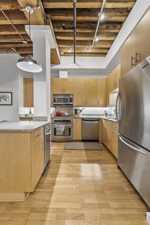 101 Broad Street, Unit 3B Boston, MA 02110 - Photo 3 of 19 a large kitchen with stainless steel appliances granite countertop a stove a sink and a refrigerator