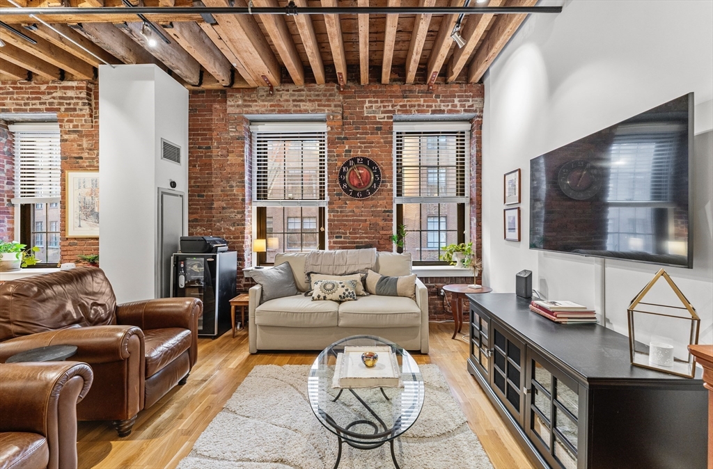 101 Broad Street, Unit 3B Boston, MA 02110 - Photo 5 of 19 a living room with furniture a flat screen tv and a floor to ceiling window