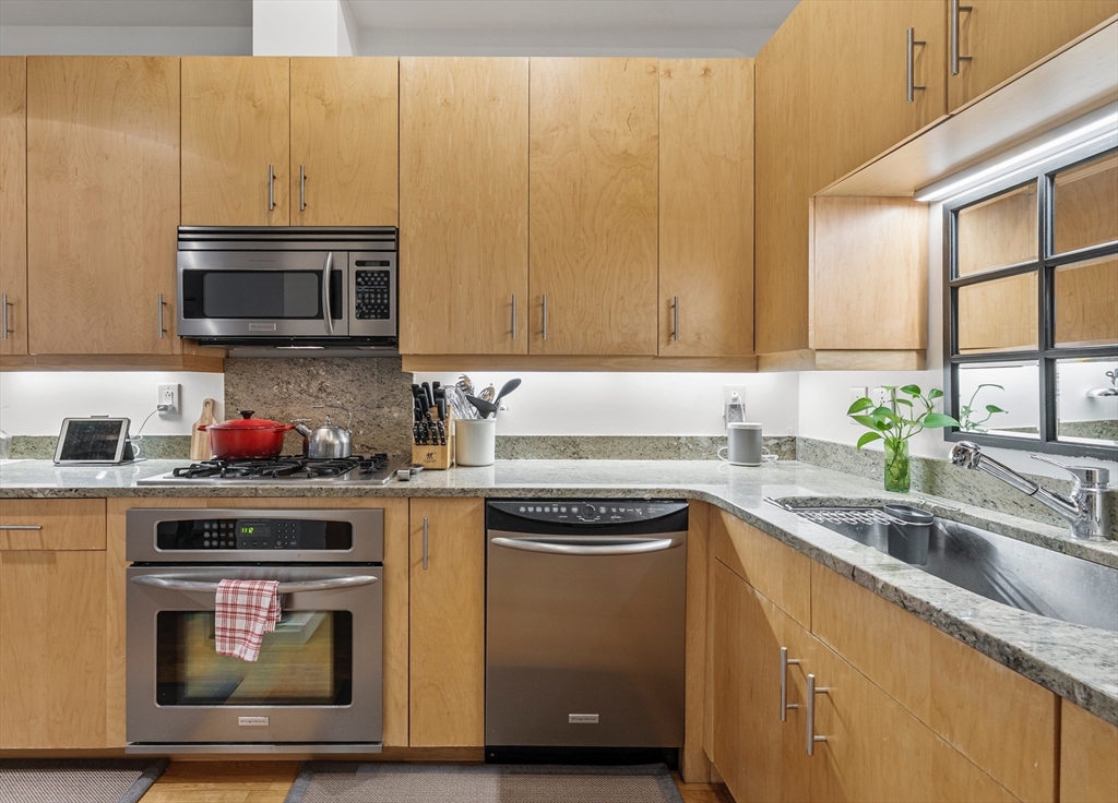 101 Broad Street, Unit 3B Boston, MA 02110 - Photo 9 of 19 a kitchen with granite countertop cabinets stainless steel appliances and a sink