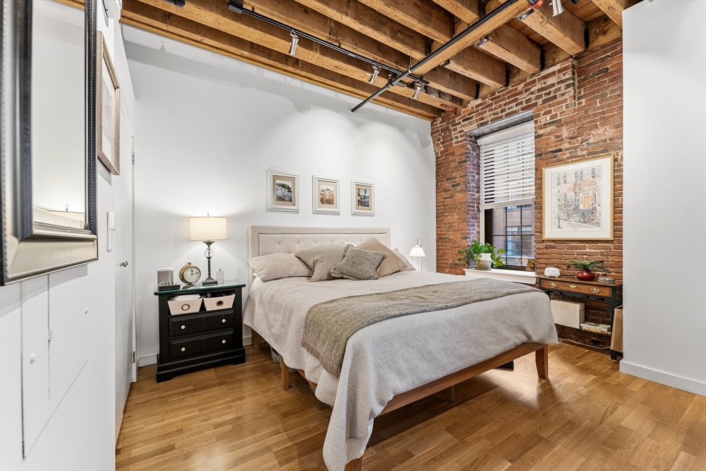 101 Broad Street, Unit 3B Boston, MA 02110 - Photo 10 of 19 a spacious bedroom with a bed and a chandelier