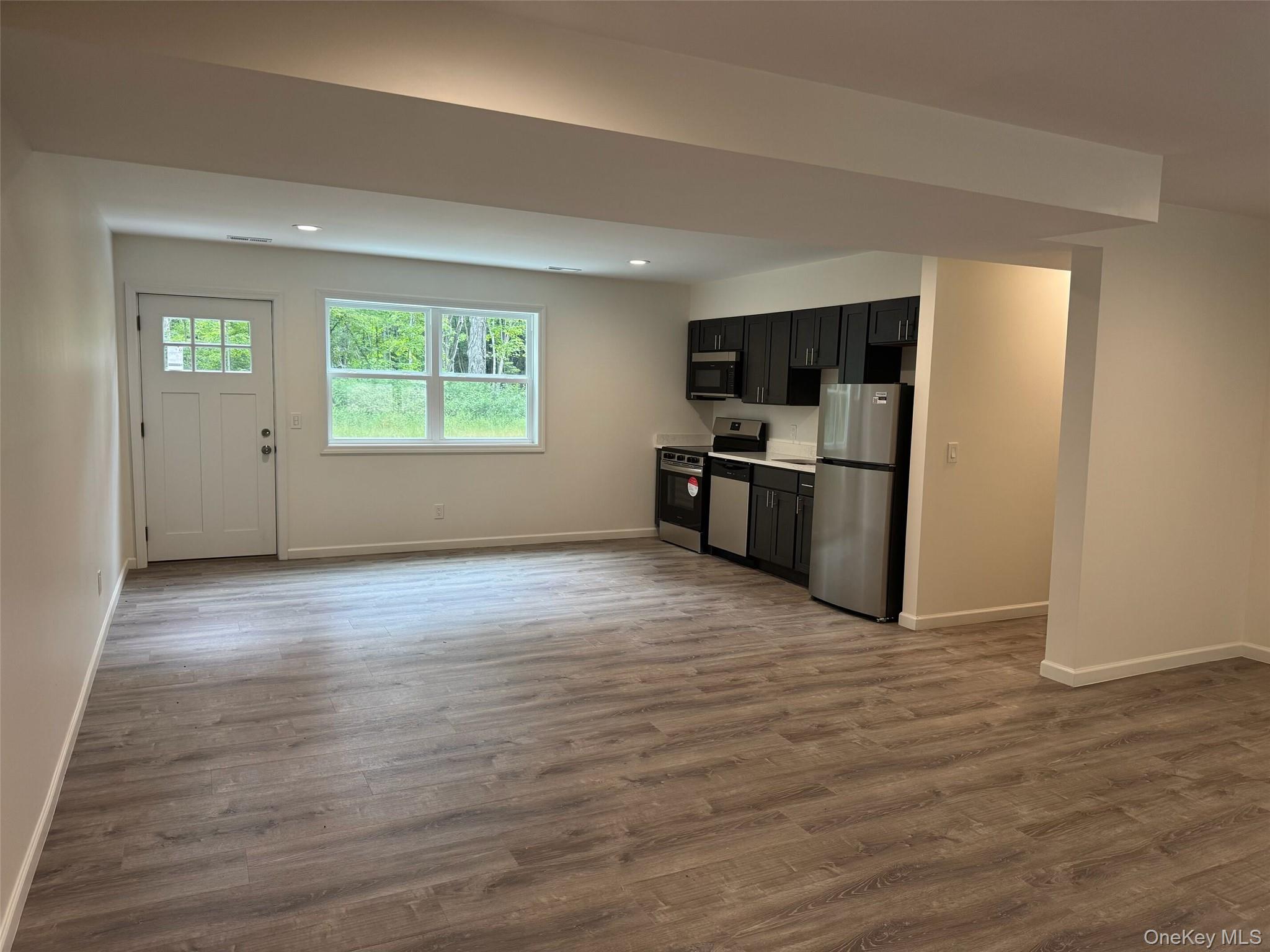 11 East Alexandra Matthews Wallkill, NY 12589 - Photo 2 of 9 Kitchen featuring open concept plus appliances with stainless steel finishes, light countertops, dark cabinets, light wood-style flooring. Door to yard.