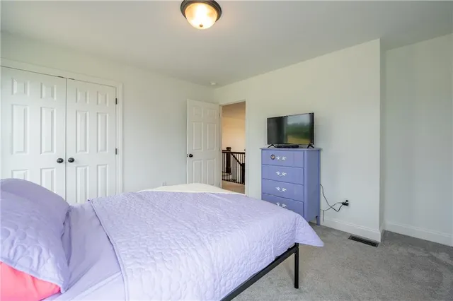 a bedroom with a bed and a flat tv screen on dresser