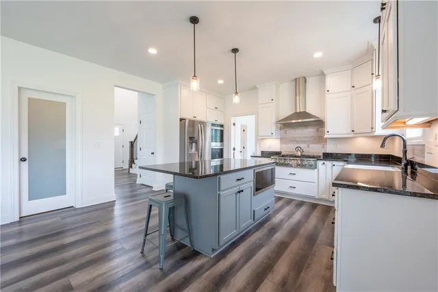 a kitchen with granite countertop a stove a sink a kitchen island with a dining table and chairs