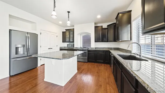 a kitchen with a sink stove a refrigerator and a oven with wooden floor
