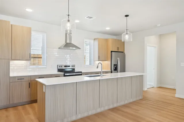 a kitchen with stainless steel appliances a sink a refrigerator a center island and cabinets