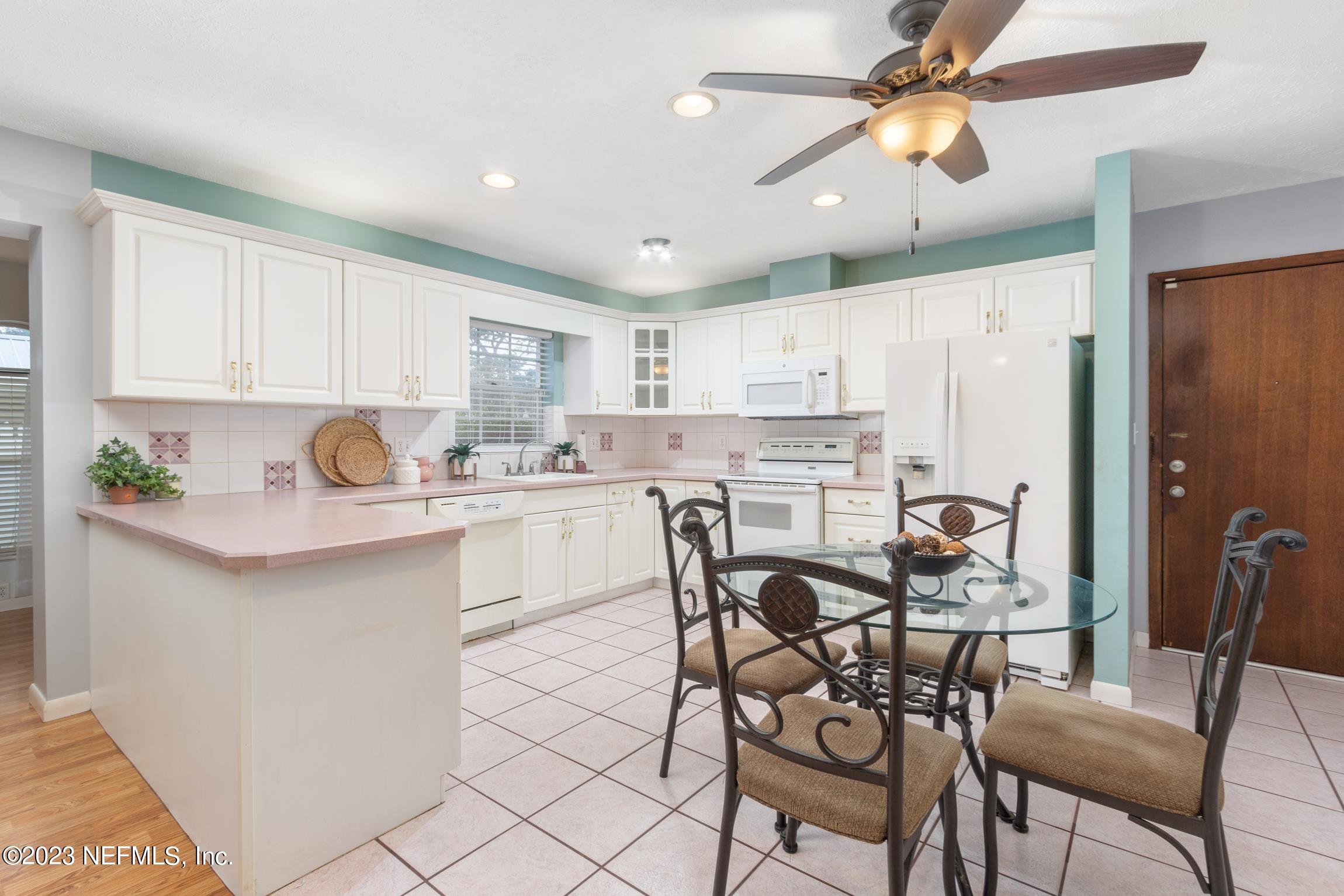 1131 Prince Road St. Augustine, FL 32086 - Photo 6 of 29 a kitchen with stainless steel appliances a white refrigerator a microwave a dining table and chairs with wooden floor