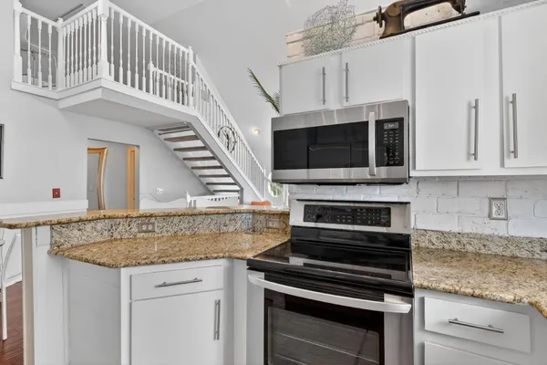 a kitchen with granite countertop a stove and a microwave