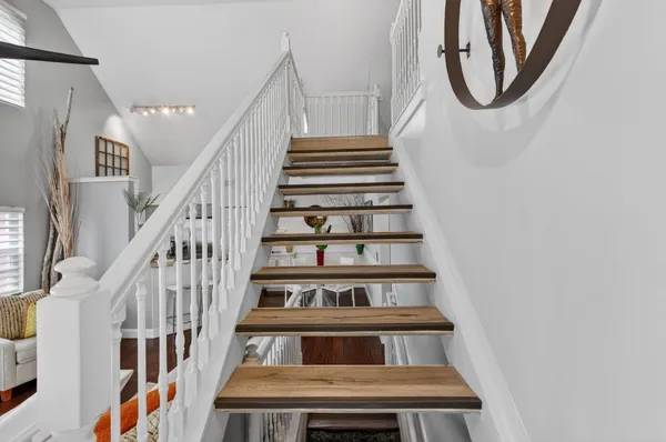a view of staircase with wooden floor and white walls