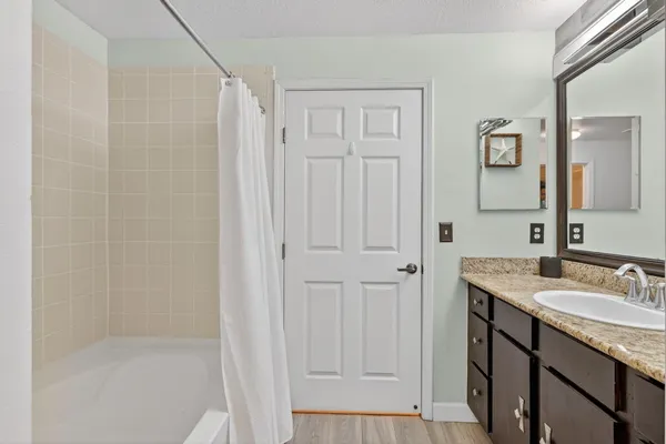 a bathroom with a granite countertop sink a mirror and a shower