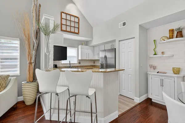 a kitchen with stainless steel appliances granite countertop a dining table chairs and a refrigerator