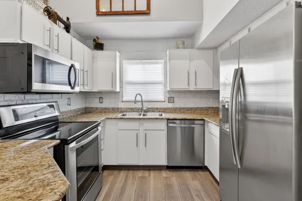 a kitchen with stainless steel appliances granite countertop a stove a sink dishwasher a refrigerator and cabinets with wooden floor