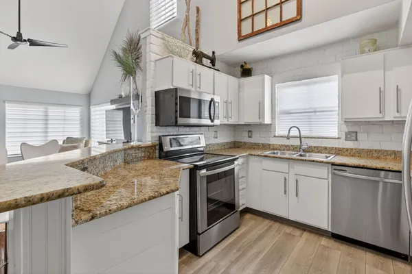 a kitchen with stainless steel appliances granite countertop a sink a stove a microwave a sink and cabinets