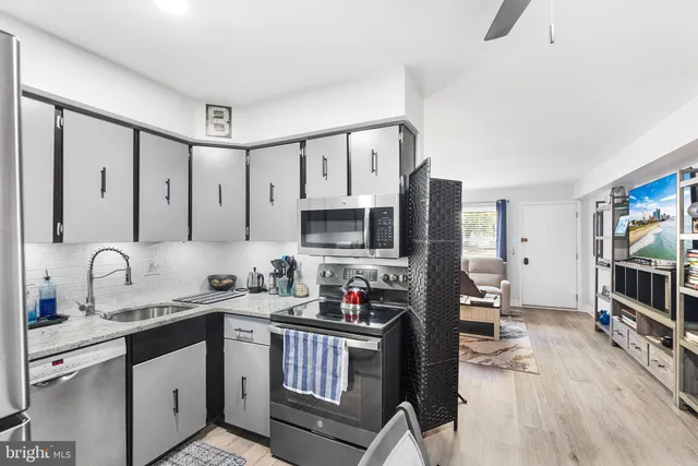 a kitchen with stainless steel appliances a sink cabinets and wooden floor