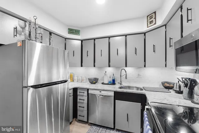 a kitchen with stainless steel appliances granite countertop a refrigerator a stove and a sink