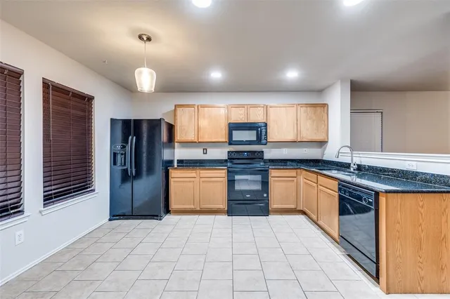 a large kitchen with stainless steel appliances kitchen island granite countertop a refrigerator and a stove top oven