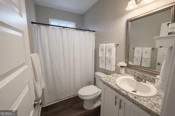 a bathroom with a granite countertop sink toilet and a mirror
