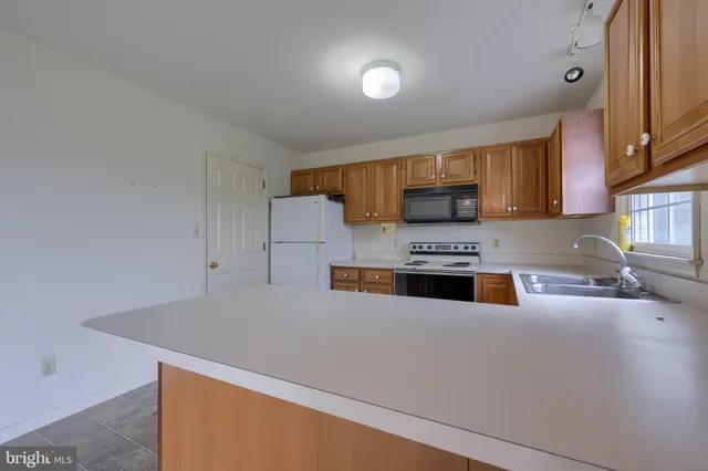 a large kitchen with kitchen island a large counter top space a sink stainless steel appliances and cabinets