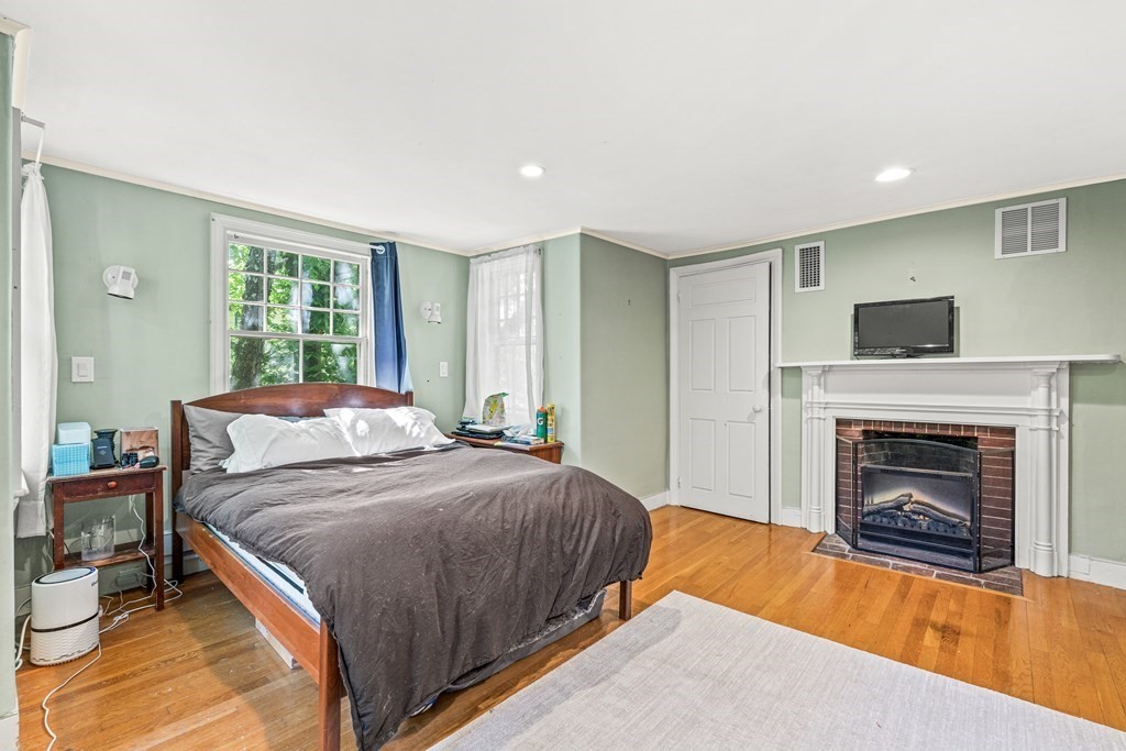 288 Mill Street Newton, MA 02460 - Photo 22 of 35 a spacious bedroom with a bed and a fireplace