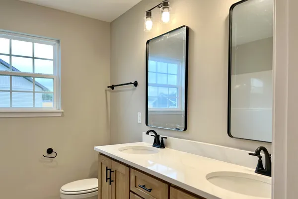 a bathroom with a granite countertop sink toilet and mirror