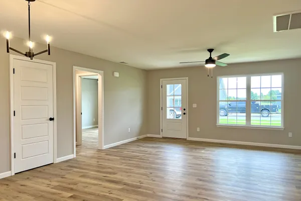 a view of an empty room with window and wooden floor