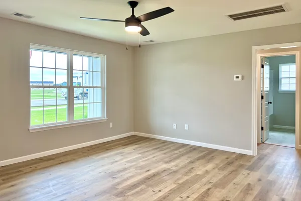 a view of empty room with wooden floor and fan