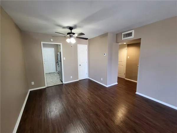 an empty room with wooden floor and a ceiling fan