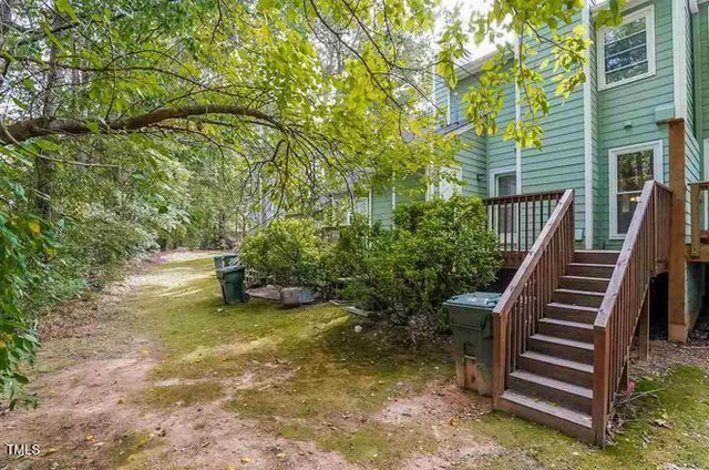 a view of a backyard with plants and a lawn chairs with wooden fence