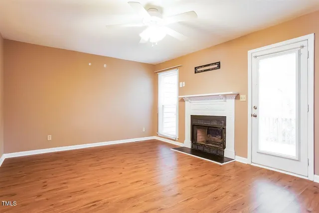 a view of empty room with wooden floor and fireplace