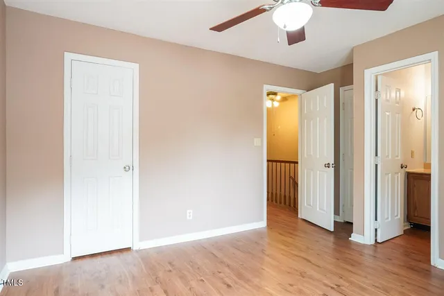 an empty room with wooden floor and a ceiling fan