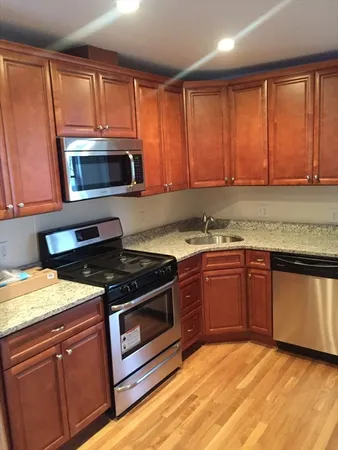 a kitchen with granite countertop wooden cabinets stainless steel appliances and a window